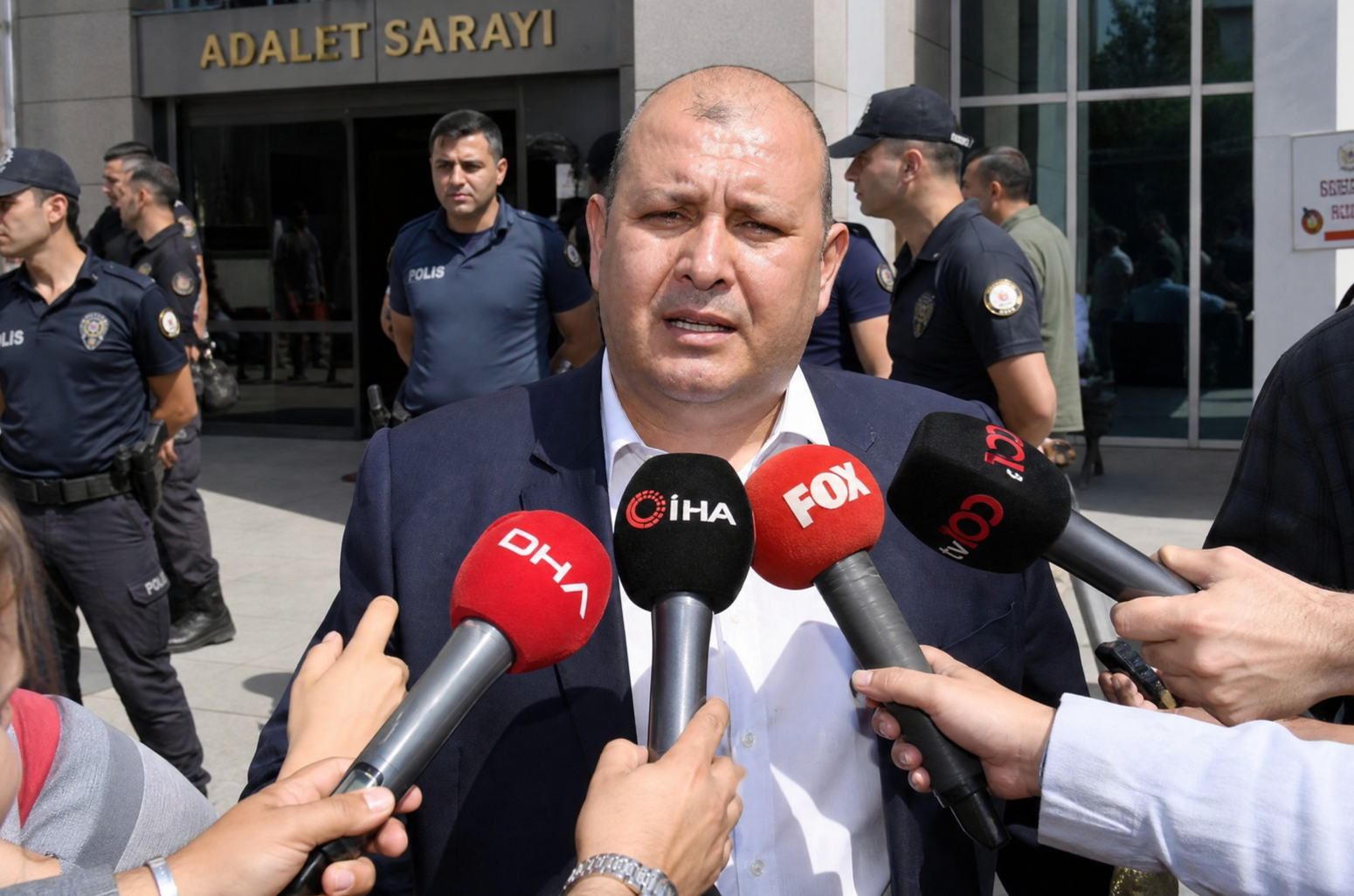 İlkay Çiçek, İzmir Adalet Sarayı önünde basın mensuplarına açıklama yapıyor. DHA, İHA ve FOX mikrofonları yüzünün birkaç santimetre uzağında.